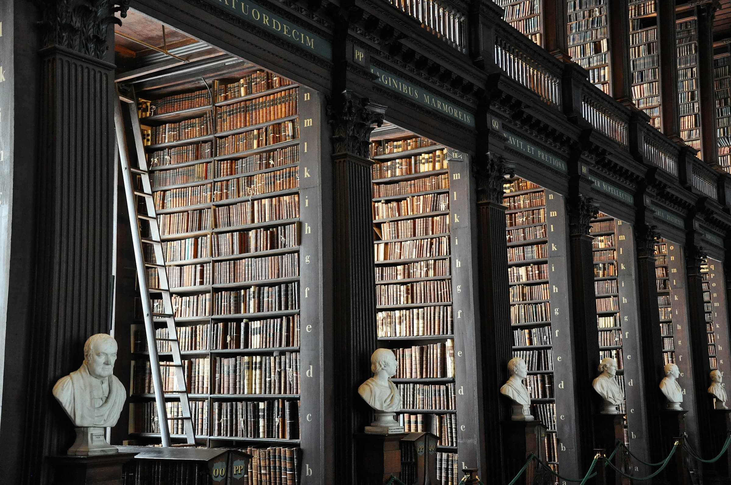 The Long Room — a grand two-storey library corridor lined with towering shelves of leather-bound volumes