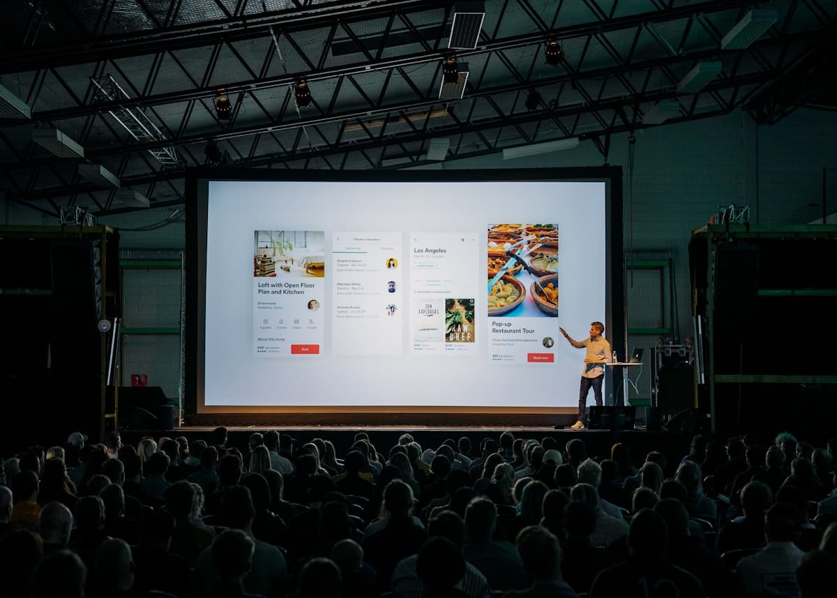 A presenter speaking in front of a large screen